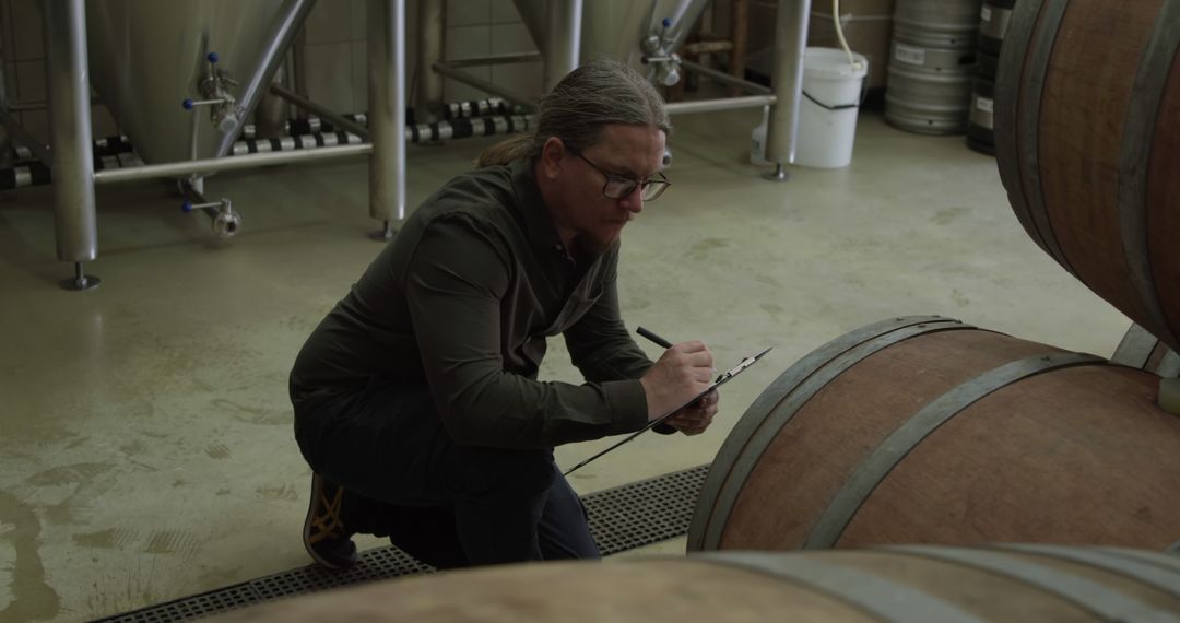 Winemaker Taking Notes While Examining Wine Barrels in Cellar - Free Images, Stock Photos and Pictures on Pikwizard.com