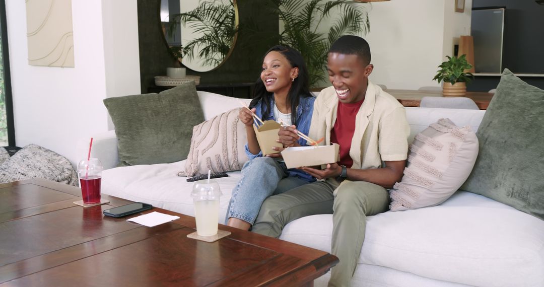 Friends Sharing Takeout with Chopsticks on Cozy Sofa