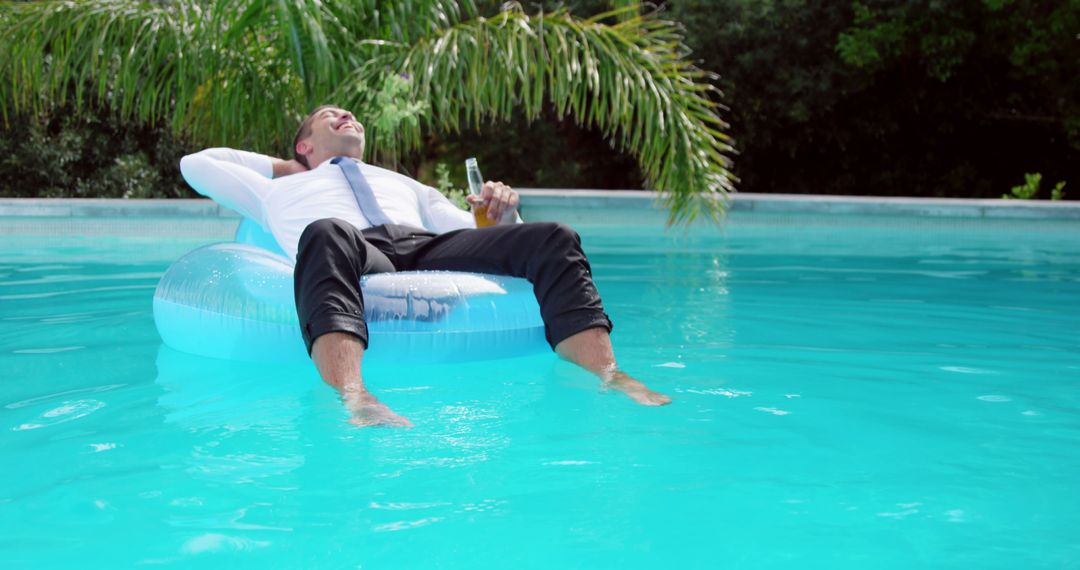 Businessman Relaxing with Drink on Pool Float in Tropical Setting - Free Images, Stock Photos and Pictures on Pikwizard.com