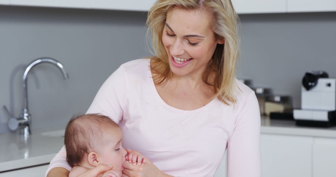 Smiling Mother Holding Baby in Kitchen - Free Images, Stock Photos and Pictures on Pikwizard.com