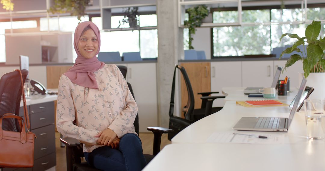 Smiling Businesswoman Wearing Hijab Sitting at Office Desk - Free Images, Stock Photos and Pictures on Pikwizard.com