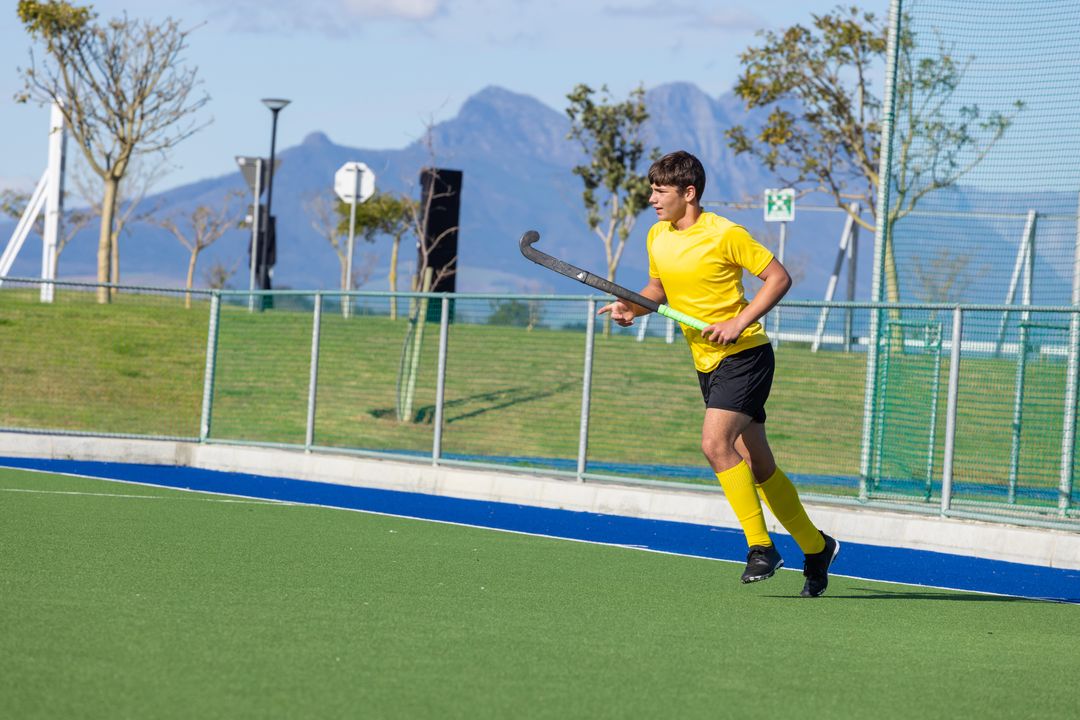 Field Hockey Player in Action on Green Turf with Scenic Mountain View