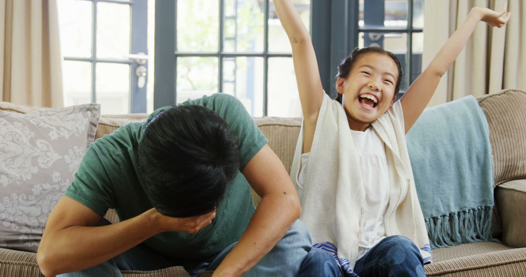 Happy Daughter Celebrating Victory While Dad Loses in Game - Free Images, Stock Photos and Pictures on Pikwizard.com