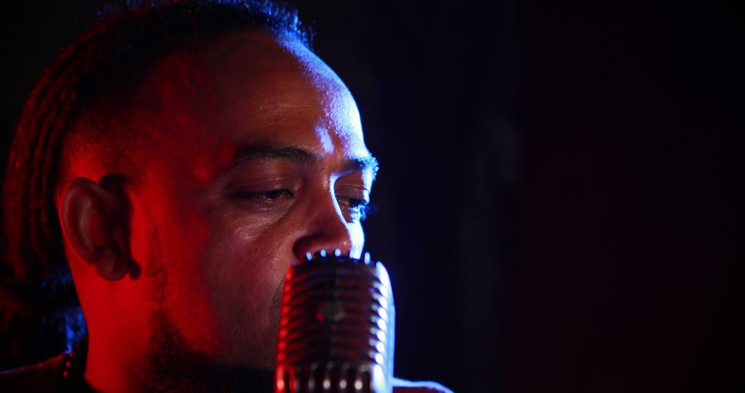 Close-up of male singer with vintage microphone in dark studio - Free Images, Stock Photos and Pictures on Pikwizard.com