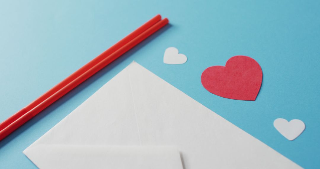 Valentine's Day Envelope with Red Straws and Paper Hearts on Blue Background