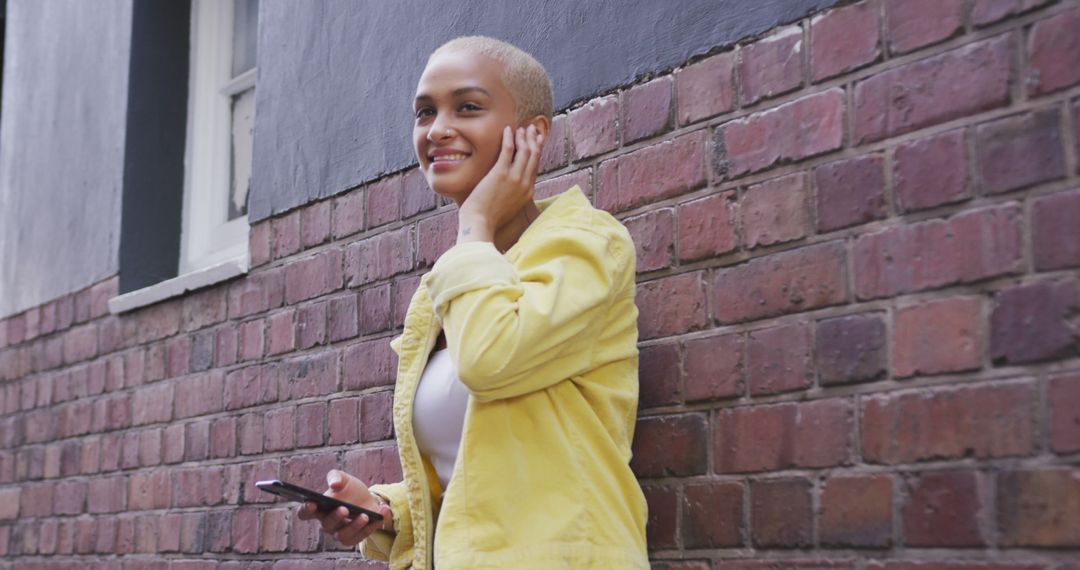 Smiling Woman With Short Hair Using Smartphone on Brick Wall Background - Free Images, Stock Photos and Pictures on Pikwizard.com