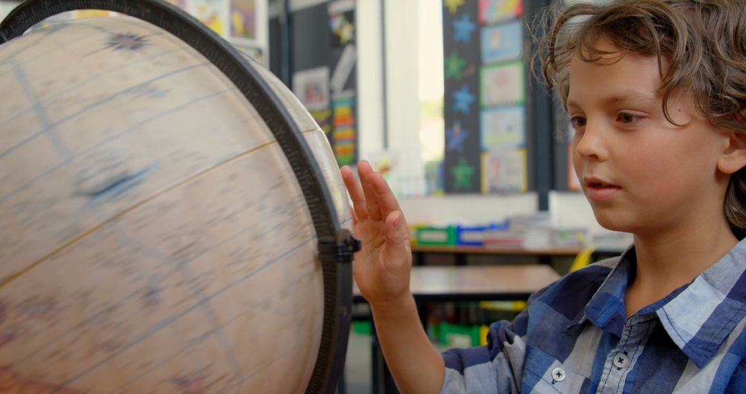 Curious Schoolboy Observing Spinning Globe in Classroom Learning Environment