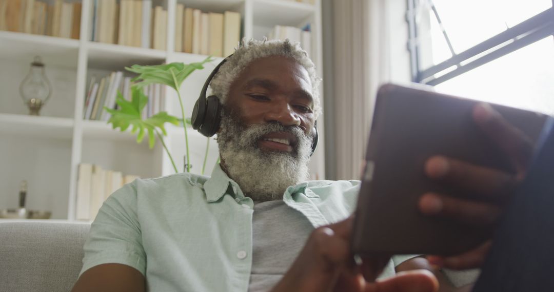 Image of african american senior man using tablet and headphones - Free Images, Stock Photos and Pictures on Pikwizard.com
