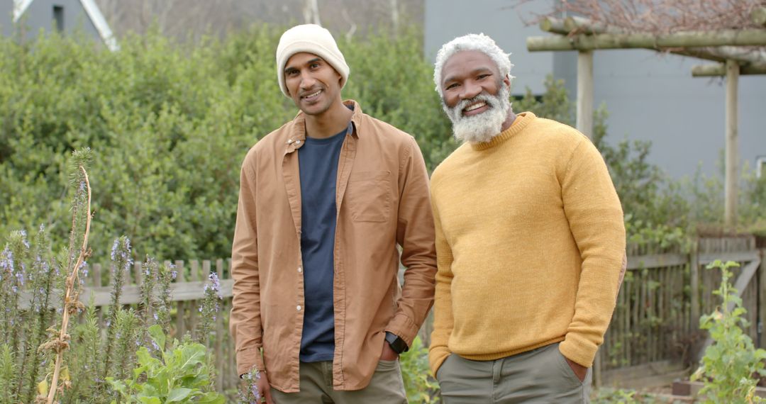 Black Elder and South Asian Younger Man Standing Smiling While Gardening in Backyard