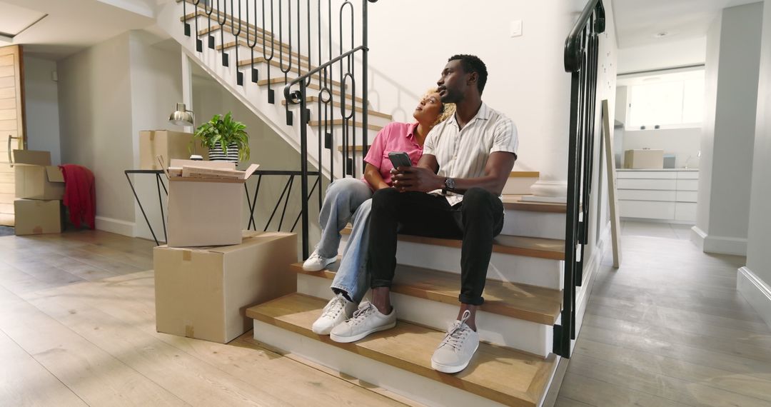 Couple Relaxing on Stairs with Moving Boxes in New Home