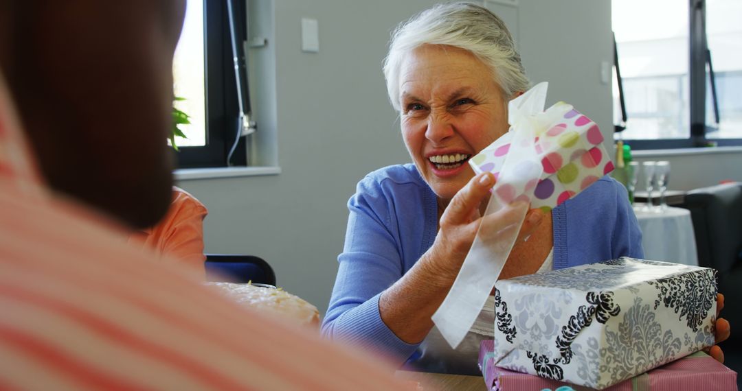 A senior Caucasian woman is joyfully receiving a gift from someone, with copy space - Free Images, Stock Photos and Pictures on Pikwizard.com