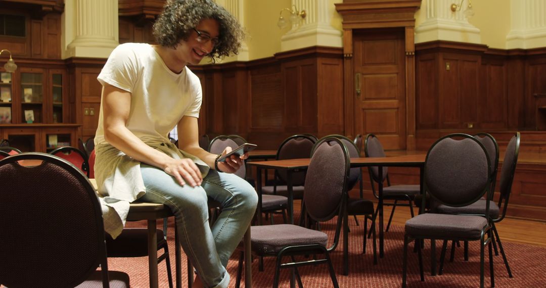 Young Man Using Phone in Serene Library Setting
