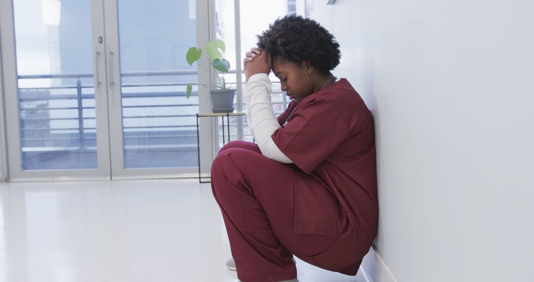 Stressed Healthcare Worker in Scrubs Sitting on Floor Praying - Free Images, Stock Photos and Pictures on Pikwizard.com