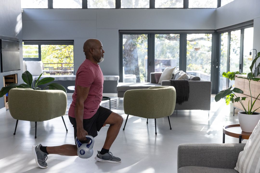 Senior Man Doing Kettlebell Lunges in Modern Living Room with Large Windows