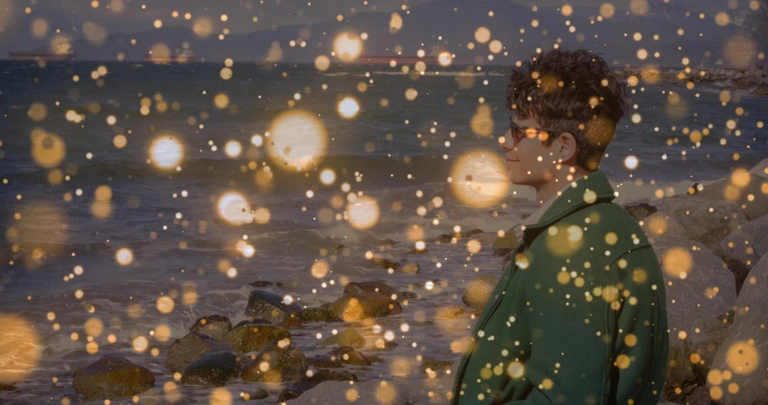 Contemplative Man at Rocky Shoreline with Glowing Lights