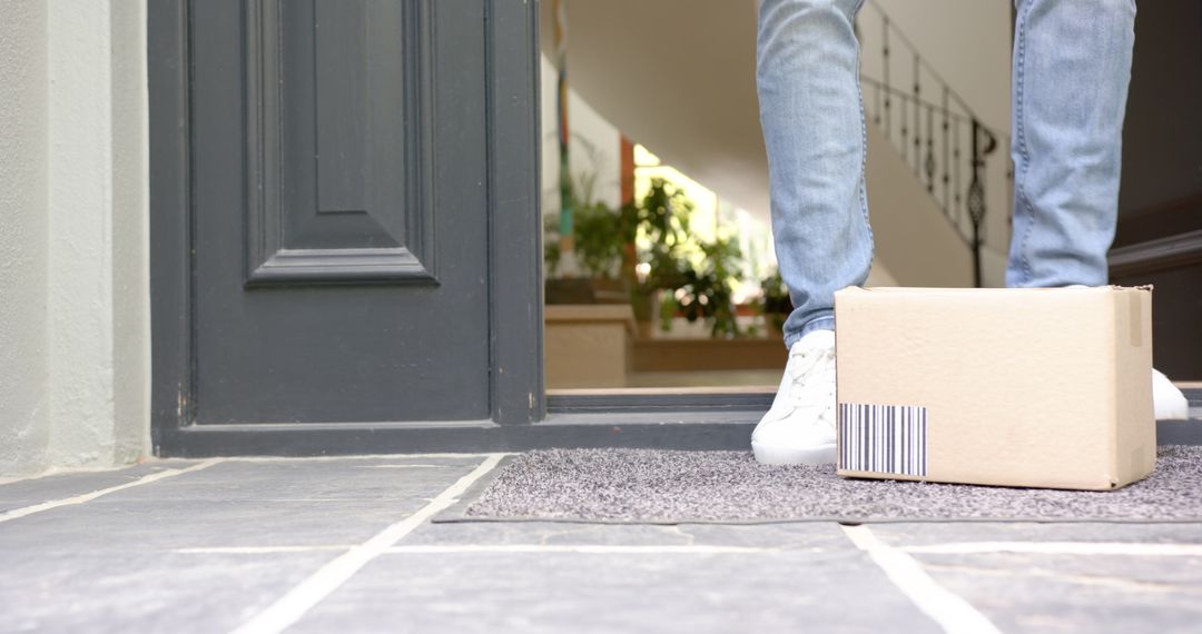Person Receiving Cardboard Package on Doorstep