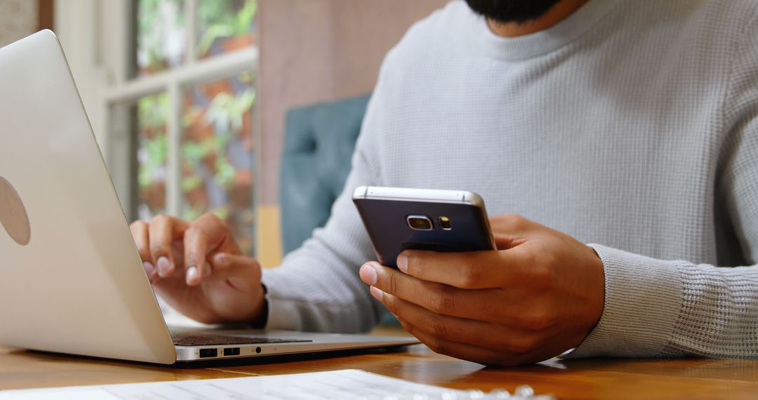 Man Multitasking with Laptop and Smartphone in Study Area