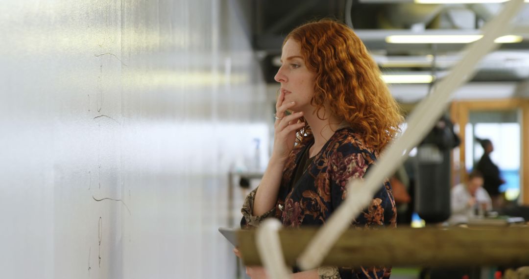 Redhead Businesswoman Examining Drawings on Whiteboard in Office - Free Images, Stock Photos and Pictures on Pikwizard.com