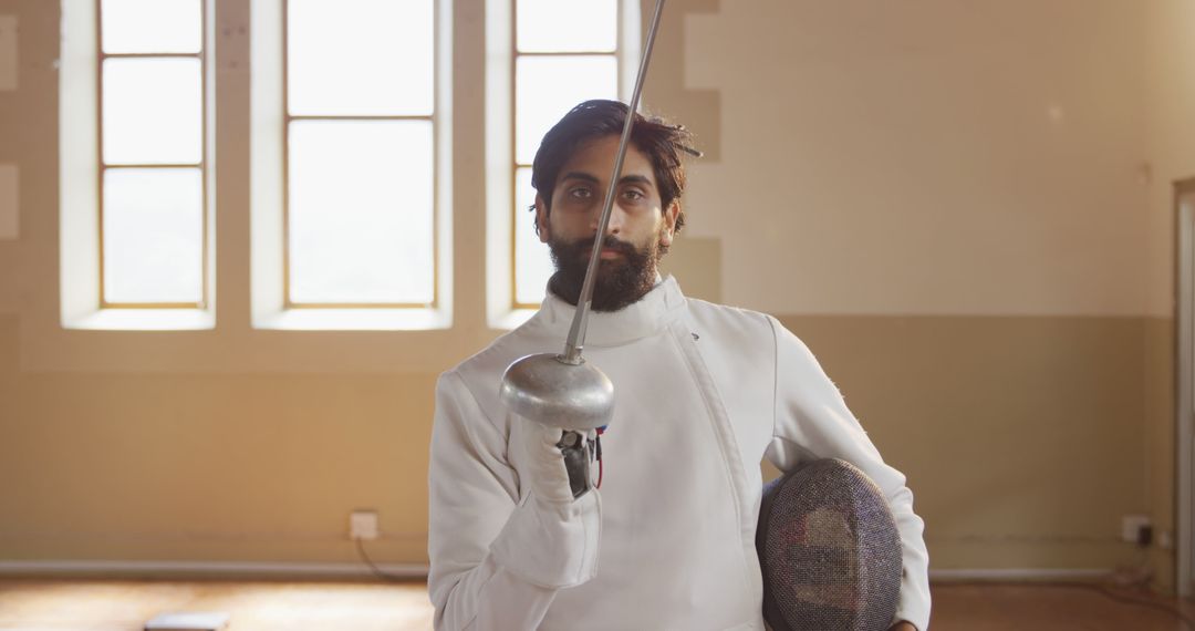 Fencer Posing with Foil Sword and Mask in Training Room - Free Images, Stock Photos and Pictures on Pikwizard.com