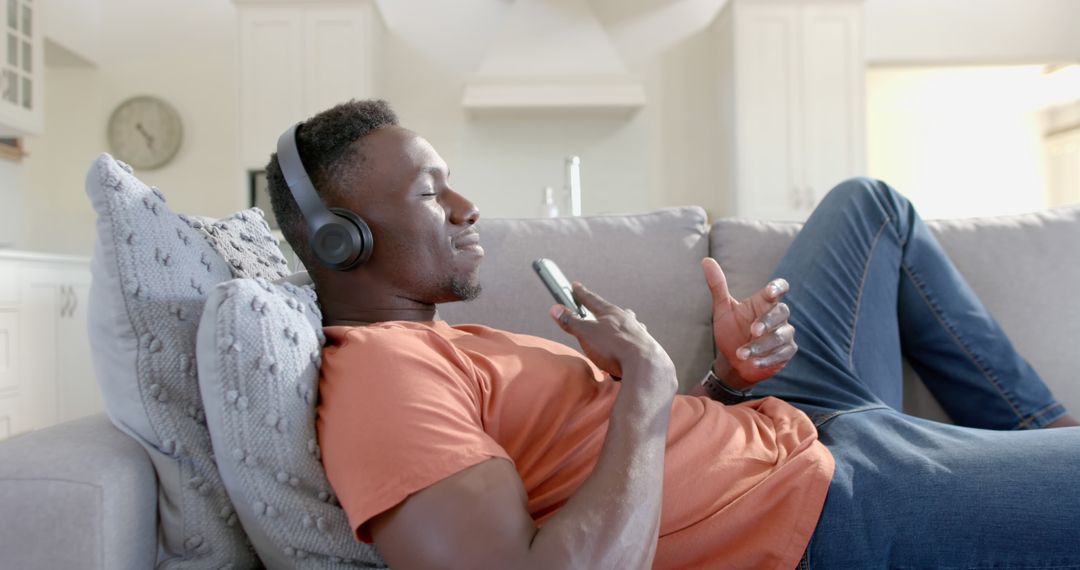 Young man relaxing on sofa listening to music with headphones - Free Images, Stock Photos and Pictures on Pikwizard.com