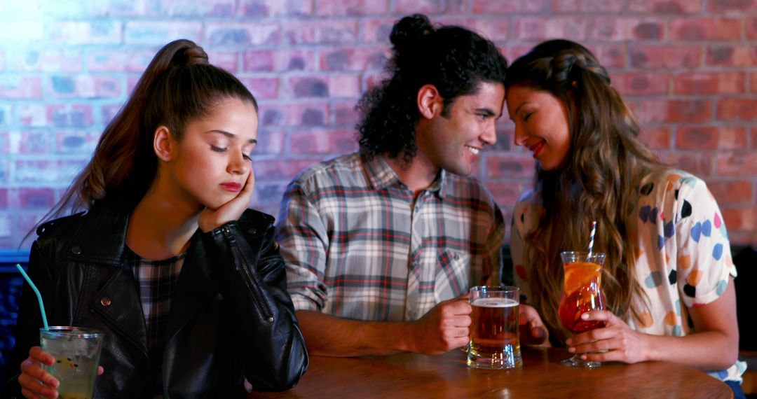 Sad Young Woman Feeling Left Out at Bar While Couple Flirts - Free Images, Stock Photos and Pictures on Pikwizard.com