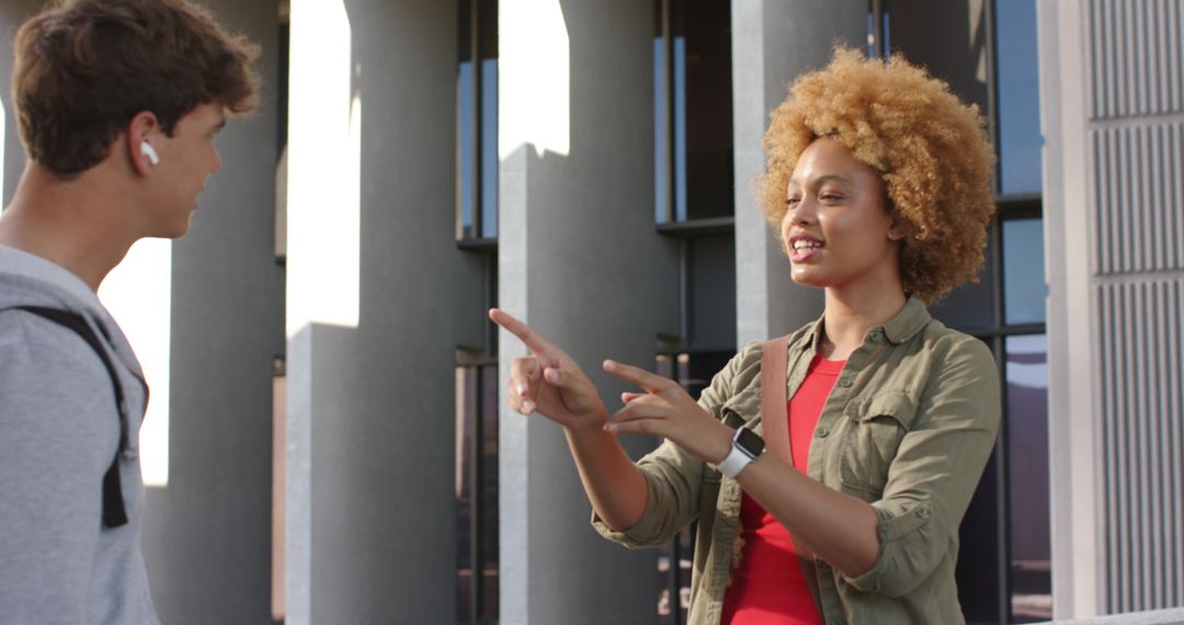 Young students chatting and pointing on modern university campus with urban architecture