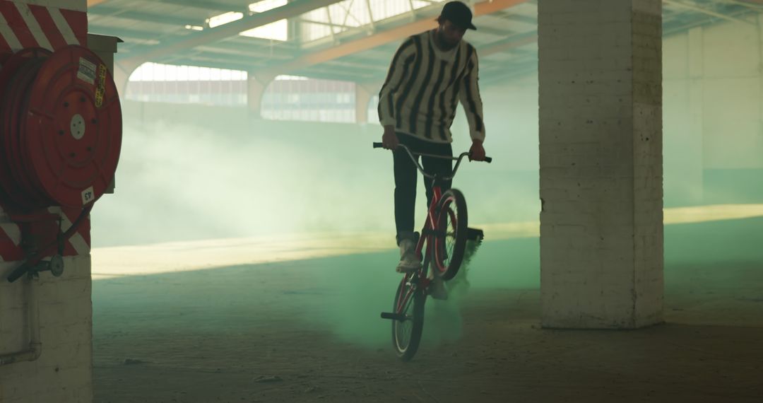 BMX Cyclist Performing Trick in Abandoned Industrial Warehouse - Free Images, Stock Photos and Pictures on Pikwizard.com