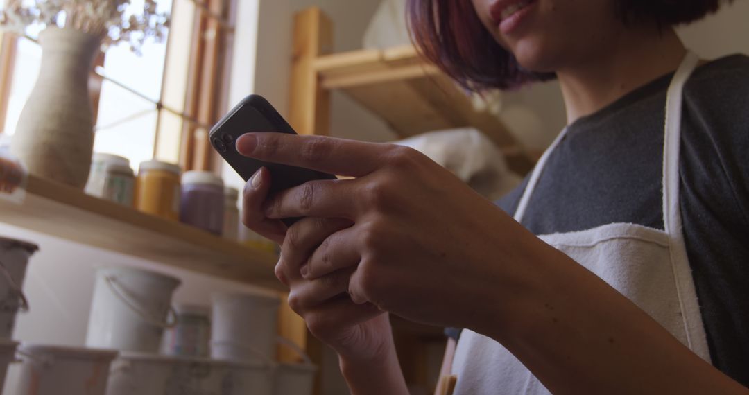 Woman Engaged in Smartphone During Pottery Work in Studio - Free Images, Stock Photos and Pictures on Pikwizard.com