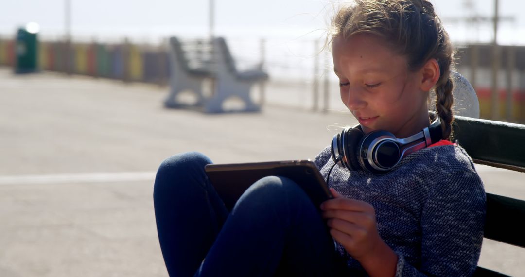 Girl Enjoying Tablet with Headphones on Sunny Day - Free Images, Stock Photos and Pictures on Pikwizard.com