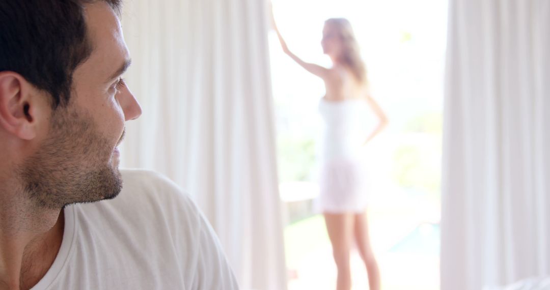 Man Observing Woman Standing Near Window With Bright Curtains - Free Images, Stock Photos and Pictures on Pikwizard.com