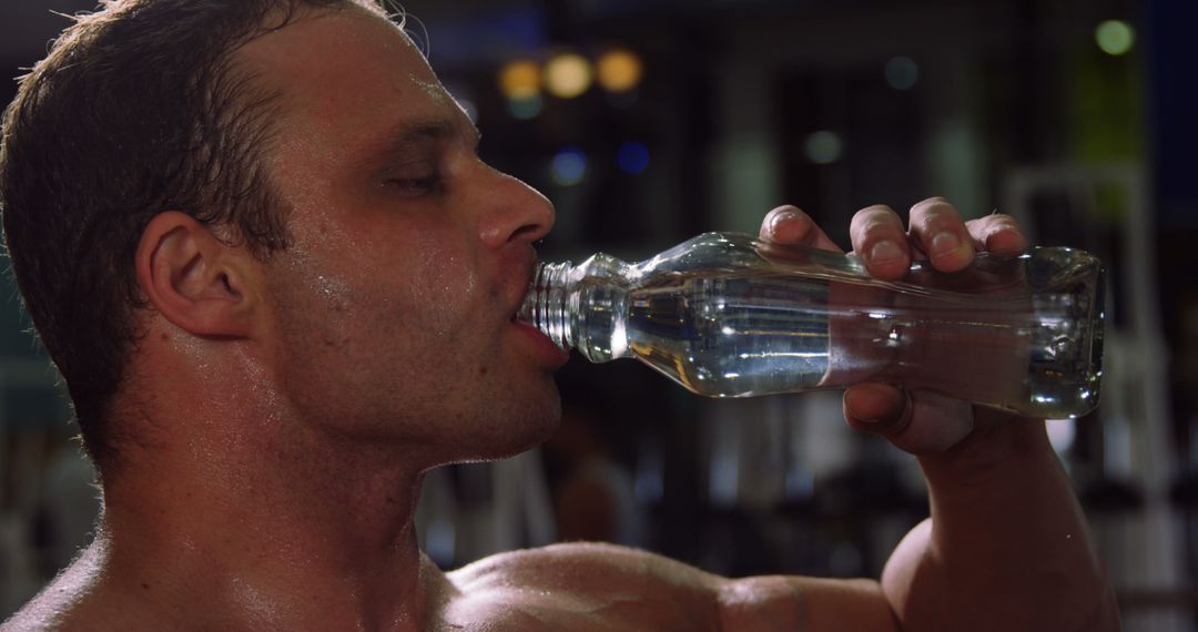 Muscular man drinking water from a bottle in gym 4k - Free Images, Stock Photos and Pictures on Pikwizard.com