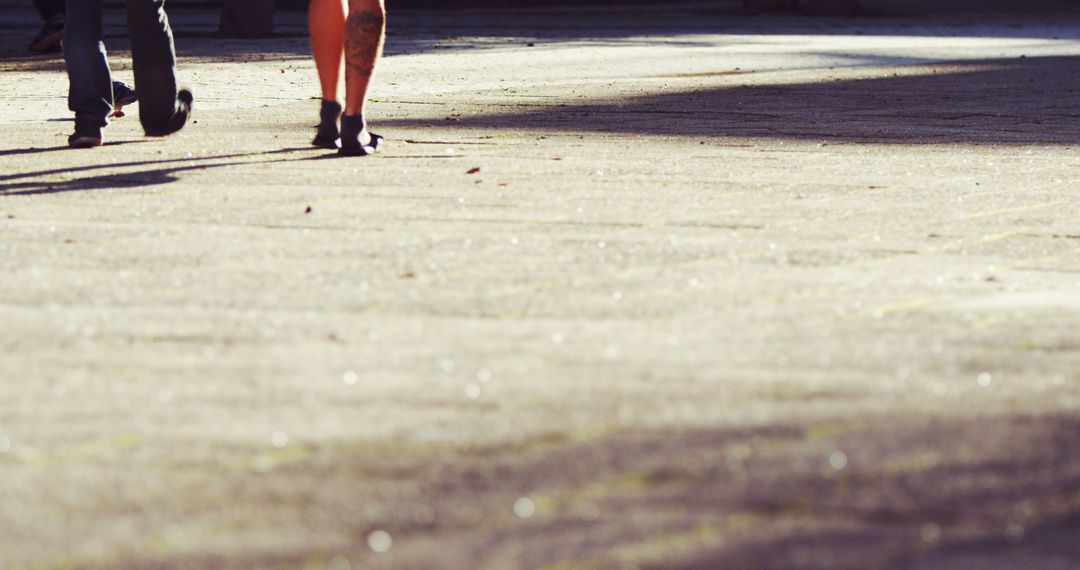 Two People Walking on Sunlit Urban Concrete Street - Free Images, Stock Photos and Pictures on Pikwizard.com