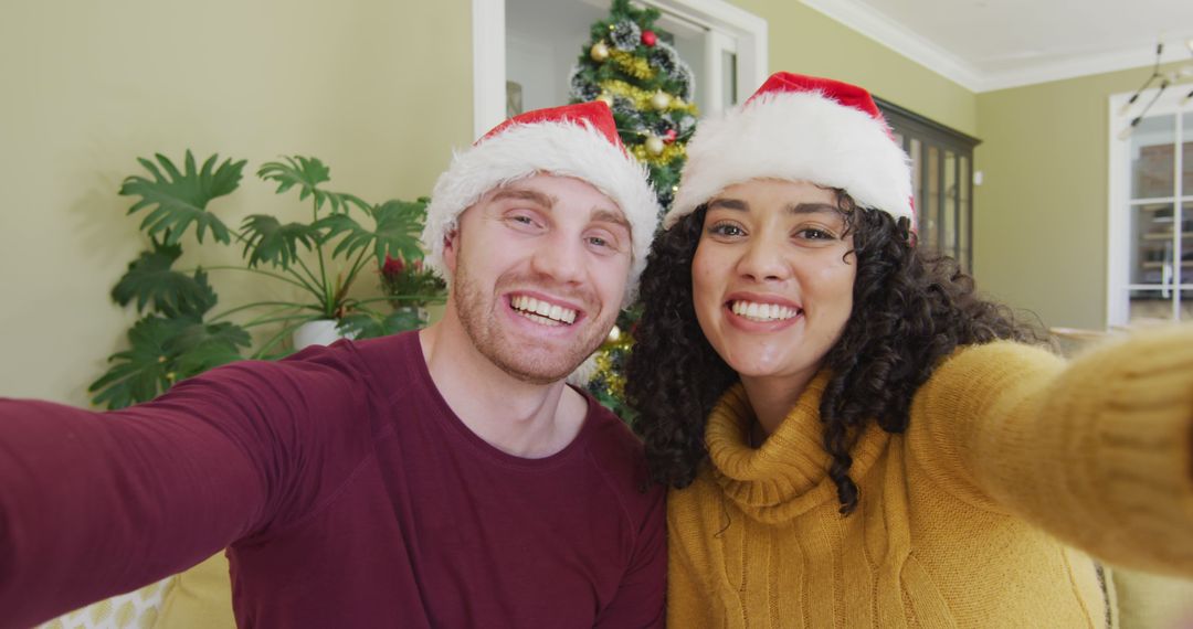 Happy Couple Taking Selfie in Front of Christmas Tree Wearing Santa Hats - Free Images, Stock Photos and Pictures on Pikwizard.com