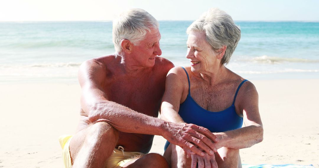 Happy Senior Couple Relaxing on Beach in Sunlight - Free Images, Stock Photos and Pictures on Pikwizard.com