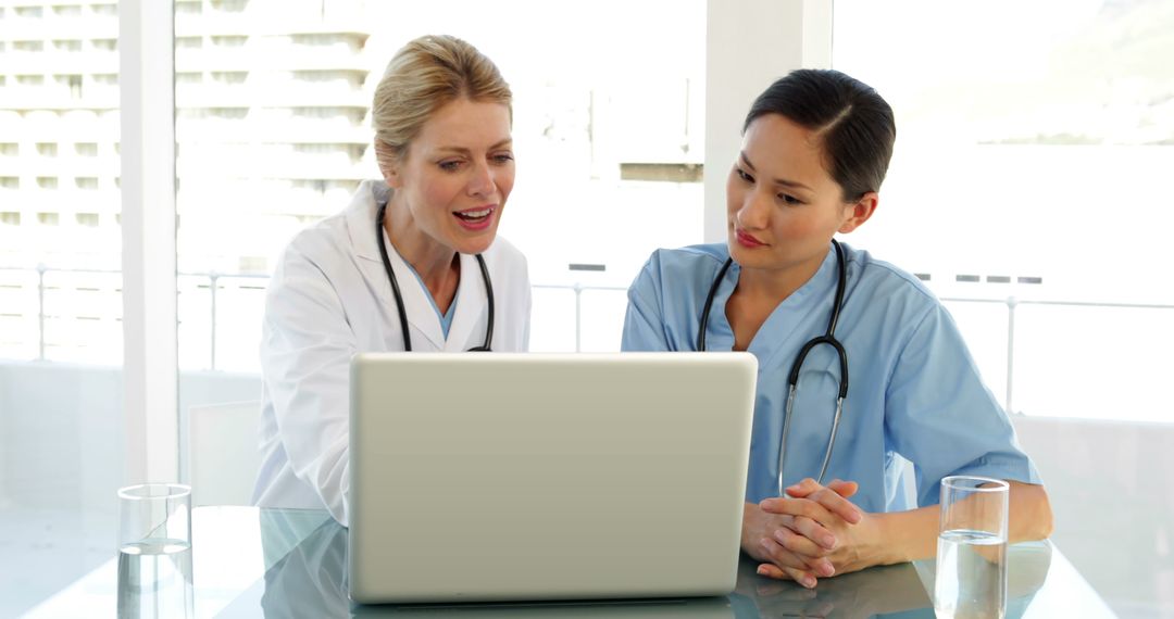 Two Female Doctors Collaborating Using Laptop in Modern Office - Free Images, Stock Photos and Pictures on Pikwizard.com