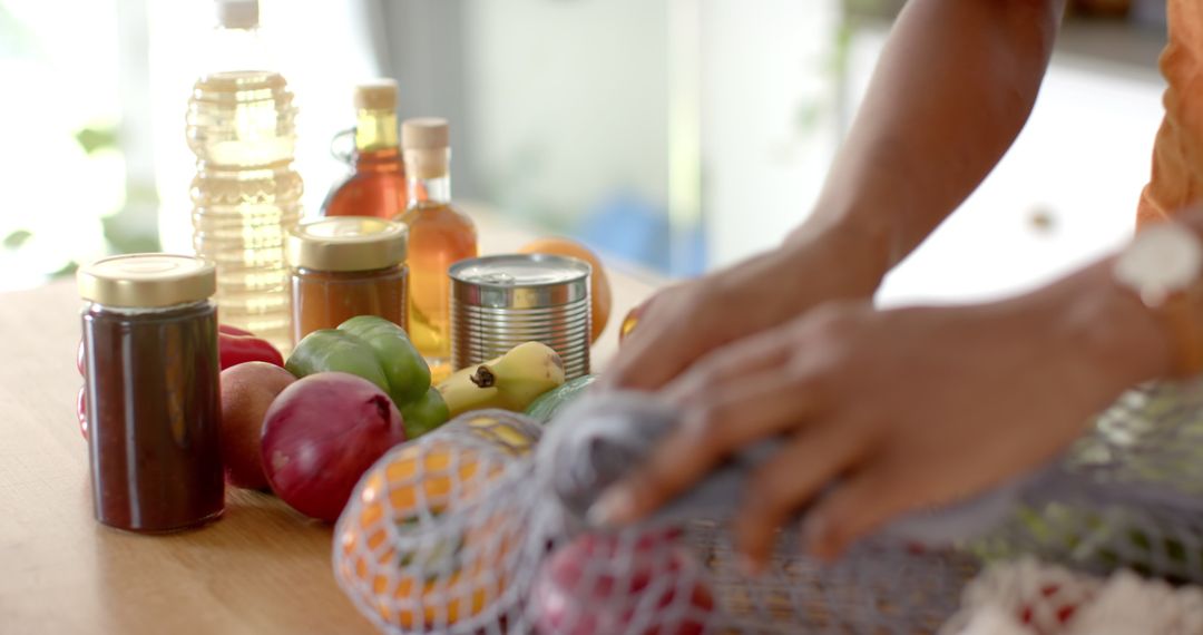 Person Arranging Fresh Produce and Jars on Kitchen Counter