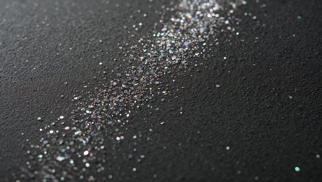Iridescent Glitter Trail Sparkling on Dark Surface with Pastel Bokeh and Macro Texture