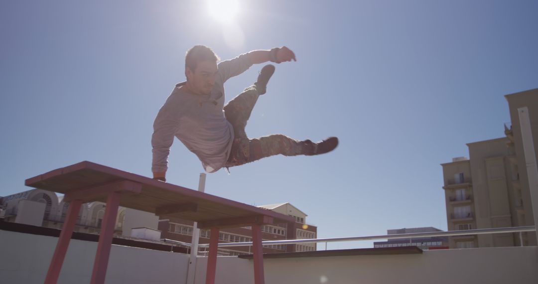 Man Performing Parkour Stunt on Rooftop in Bright Sunlight - Free Images, Stock Photos and Pictures on Pikwizard.com