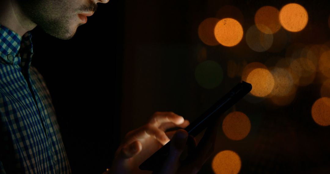 Man Using Smartphone at Night with Bokeh Lights in Background - Free Images, Stock Photos and Pictures on Pikwizard.com