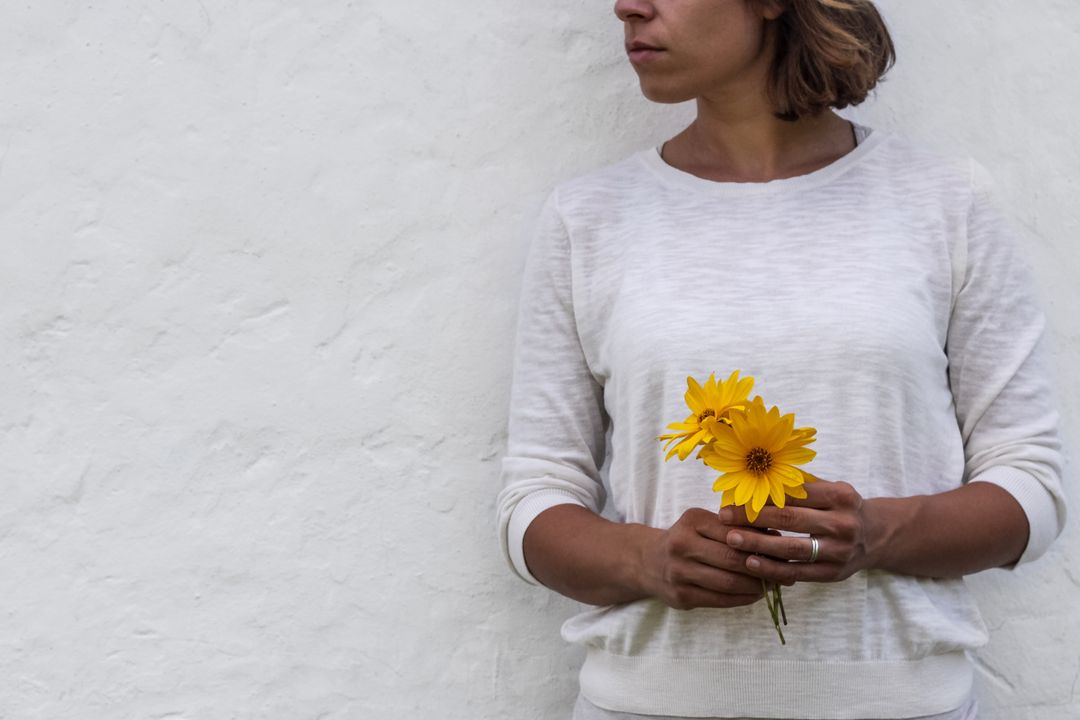 Woman Holding Sunflowers against White Wall