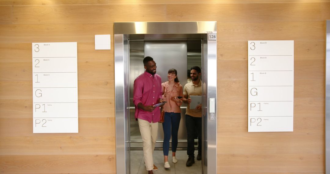 Colleagues Chatting While Exiting Elevator in Modern Office