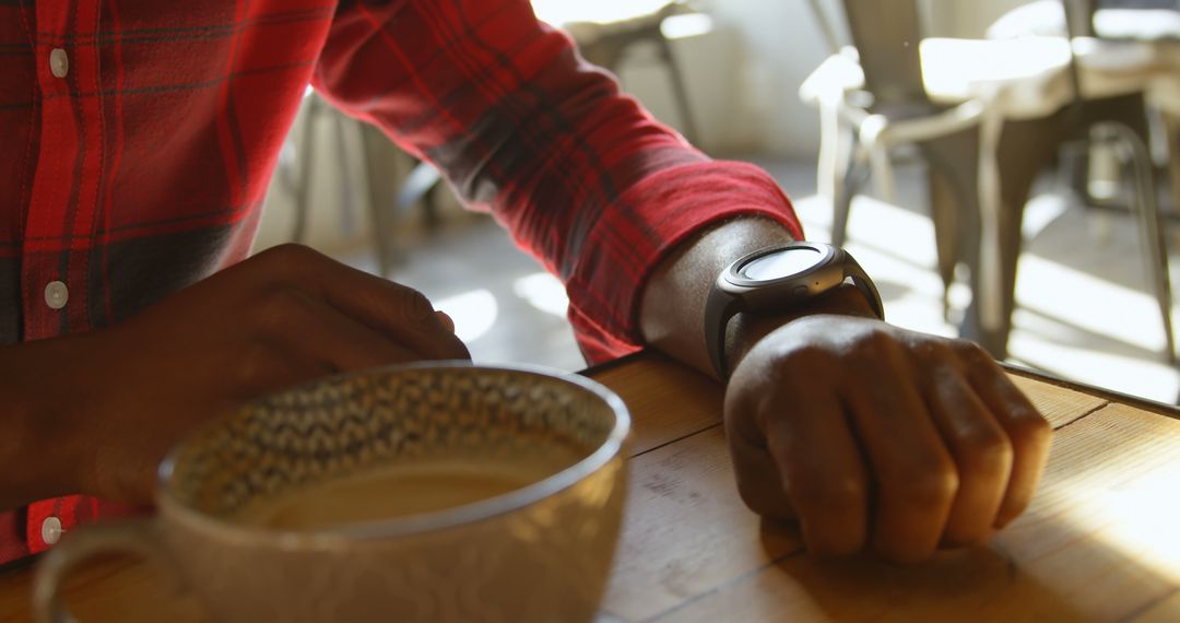 Person Checking Smartwatch at Coffee Shop with Warm Lighting - Free Images, Stock Photos and Pictures on Pikwizard.com