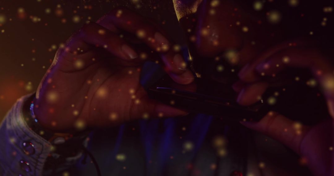 Tapping Male Hands Operating Smartphone in Dim Neon Light with Golden Bokeh and Wristband