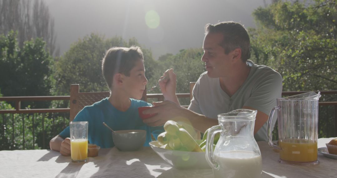 Father and son enjoying breakfast outdoors in sunny morning - Free Images, Stock Photos and Pictures on Pikwizard.com