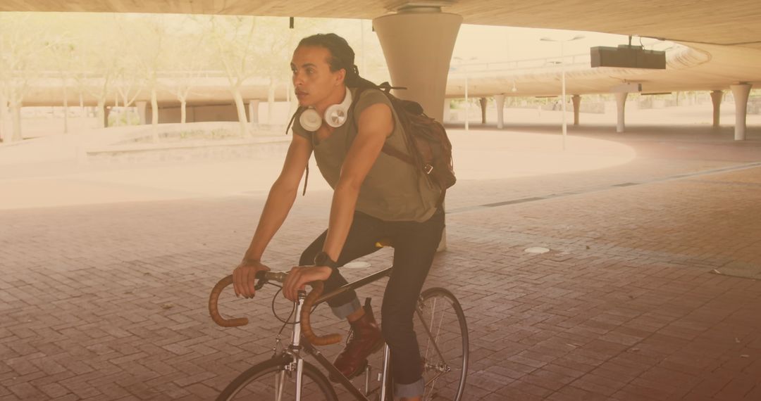 Man Cyclist Commutes Under City Bridge with Backpack