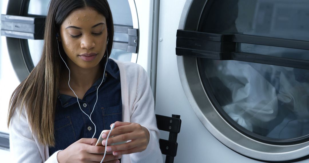 Young Woman Listening to Music in Laundromat - Free Images, Stock Photos and Pictures on Pikwizard.com