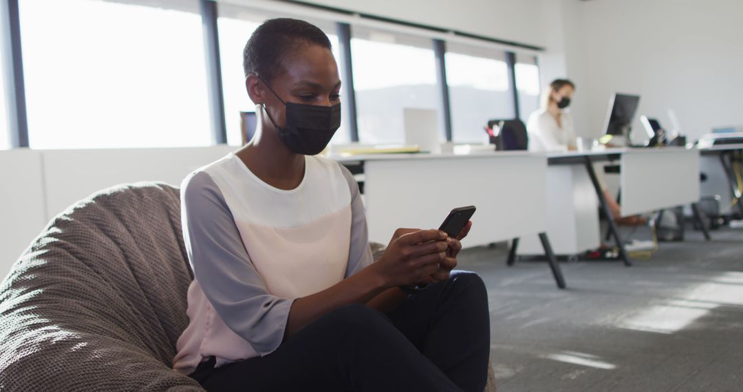 Professional Woman Wearing Face Mask, Using Smartphone in Modern Office - Free Images, Stock Photos and Pictures on Pikwizard.com