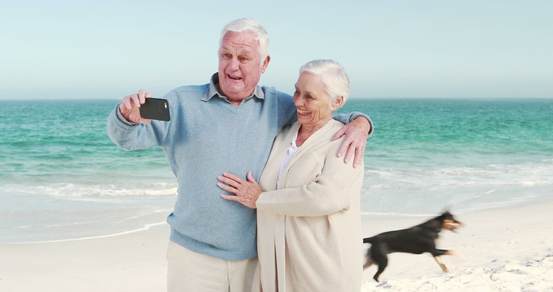 Senior Couple Taking Selfie on Beach with Dog Running by - Free Images, Stock Photos and Pictures on Pikwizard.com