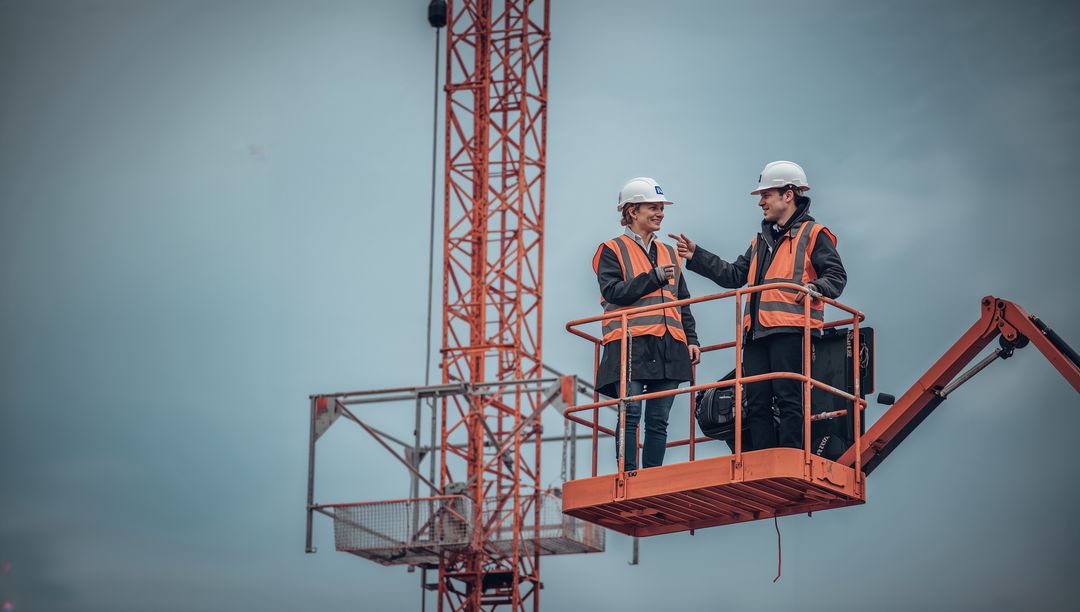 Engineers Discussing Logistics on Platform Near Construction Crane