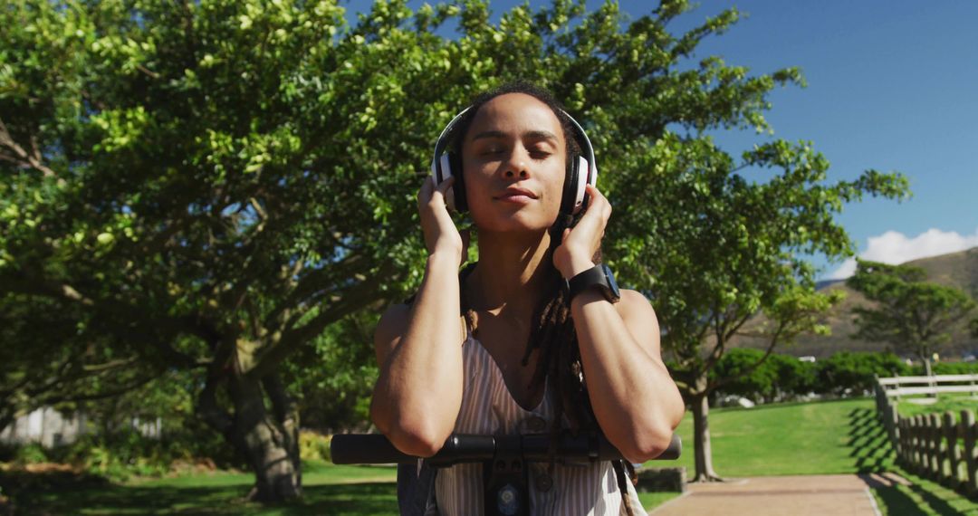 Woman Listening to Music on Headphones Front Electric Scooter Enjoying Sunny Park